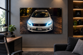 A large rectangular wall art print showing a white Honda car at night on a cobblestone street, displayed in a modern living room setting above a sofa and next to a desk.