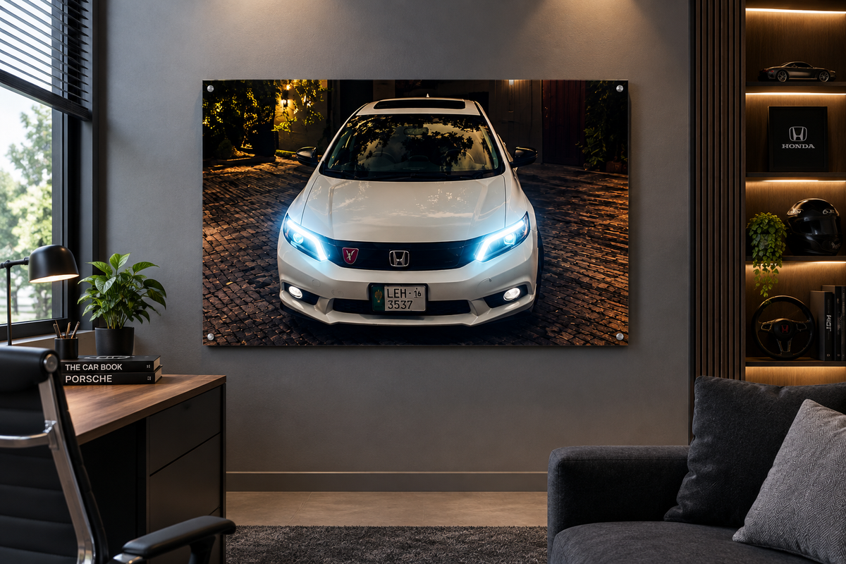 A large rectangular wall art print showing a white Honda car at night on a cobblestone street, displayed in a modern living room setting above a sofa and next to a desk.