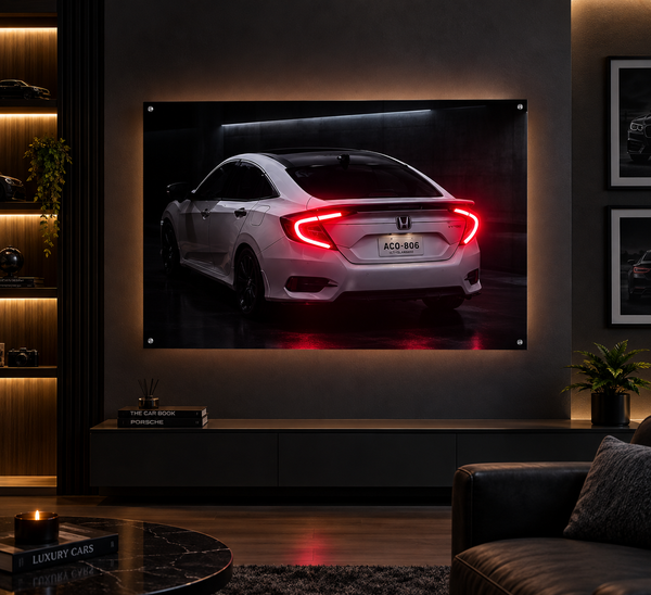 A framed wall art print showing the rear view of a white Honda sedan with illuminated red taillights, displayed in a modern dark living room above a console table.